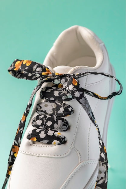 Détail des lacets noirs fleuri or, accessoire fait main et responsable par Pop lacets.