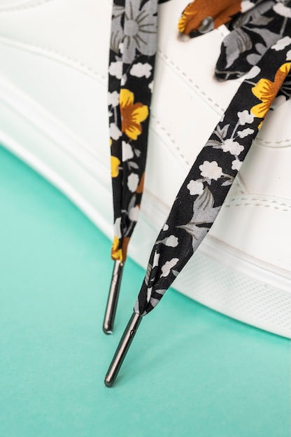 Détail des lacets noirs fleuris or, fabriqué par Pop Lacets avec des tissus de seconde main.